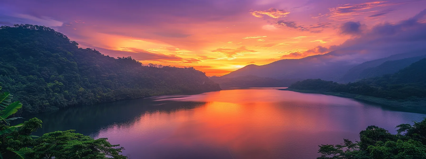 a breathtaking sunset paints the sky in vivid shades of orange and purple, casting a warm glow over a tranquil lake surrounded by lush, verdant mountains.